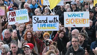 Participants hold up placards in front of the landmark Brandenburg Gate in Berlin on March 9, 2025, during a demonstration in support of Ukraine.  Image- AFP