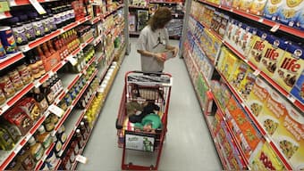 A woman looks at products in the aisle of a store as her child naps in the shopping cart. File image/AP