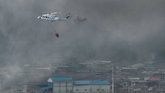 Helicopters try to extinguish a fire after a wildfire broke out in the southeastern county of Uiseong on March 22, 2025. AFP