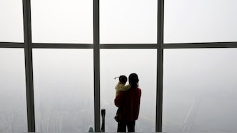 A woman holding her baby in her arms looks at a view of Seoul shrouded by fine dust during a polluted day in Seoul, South Korea, March 6, 2019. File Photo/Reuters