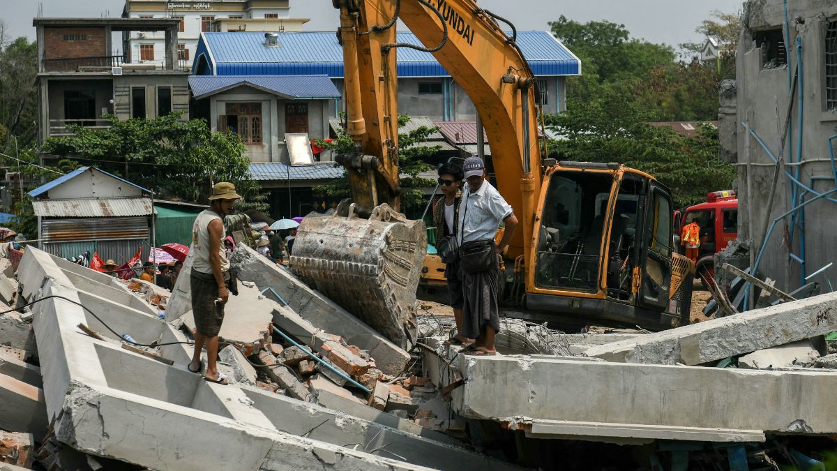 People stand next to heavy construction equipment being used to dig through the rubble of a destroyed building to look for survivors in Mandalay on March 29, 2025. AFP People stand next to heavy construction equipment being used to dig through the rubble of a destroyed building to look for survivors in Mandalay on March 29, 2025. AFP