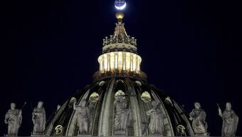 The moon moves behind the cross on top of St Peter's Basilica ahead of the recitation of the Holy Rosary for Pope Francis' health in St Peter's Square at the Vatican. AP