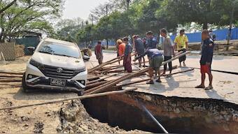 This UGC photo taken and posted by Hla Myo Aung on Facebook on March 28, 2025 shows people trying to save a vehicle from falling into a crack in the road in Sagaing, following an earthquake. Rescuers dug through the rubble of collapsed buildings on March 29 in a desperate search for survivors after a huge earthquake hit Myanmar and Thailand, killing more than 1000 people. Source: AFP