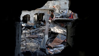 A child sits amid rubble as Palestinians inspect the site of an Israeli strike on a house, in Khan Younis in the southern Gaza Strip. Reuters