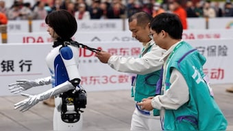 Engineers run with a humanoid robot. Reuters