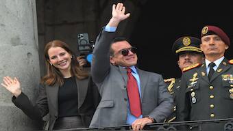 Ecuador's reelected President Daniel Noboa (C) waves to supporters accompanied by his wife, Lavinia Valbonesi (L) and the chief of the Presidential Military House, Milton Rodriguez, from a balcony of the Carondelet Presidential Palace during the changing of the guard ceremony in Quito on April 15, 2025. AFP
