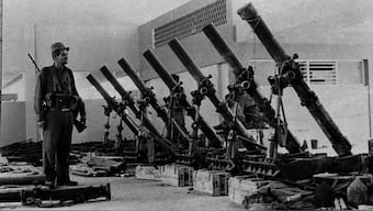 A soldier of the Cuban Armed Forces stands next to US-built armaments captured after some 1,500 anti-Castro allies came ashore at Playa Giron beach during the Bay of Pigs invasion on the south coast of Cuba, in this April 1961 photo. File Image/Reuters