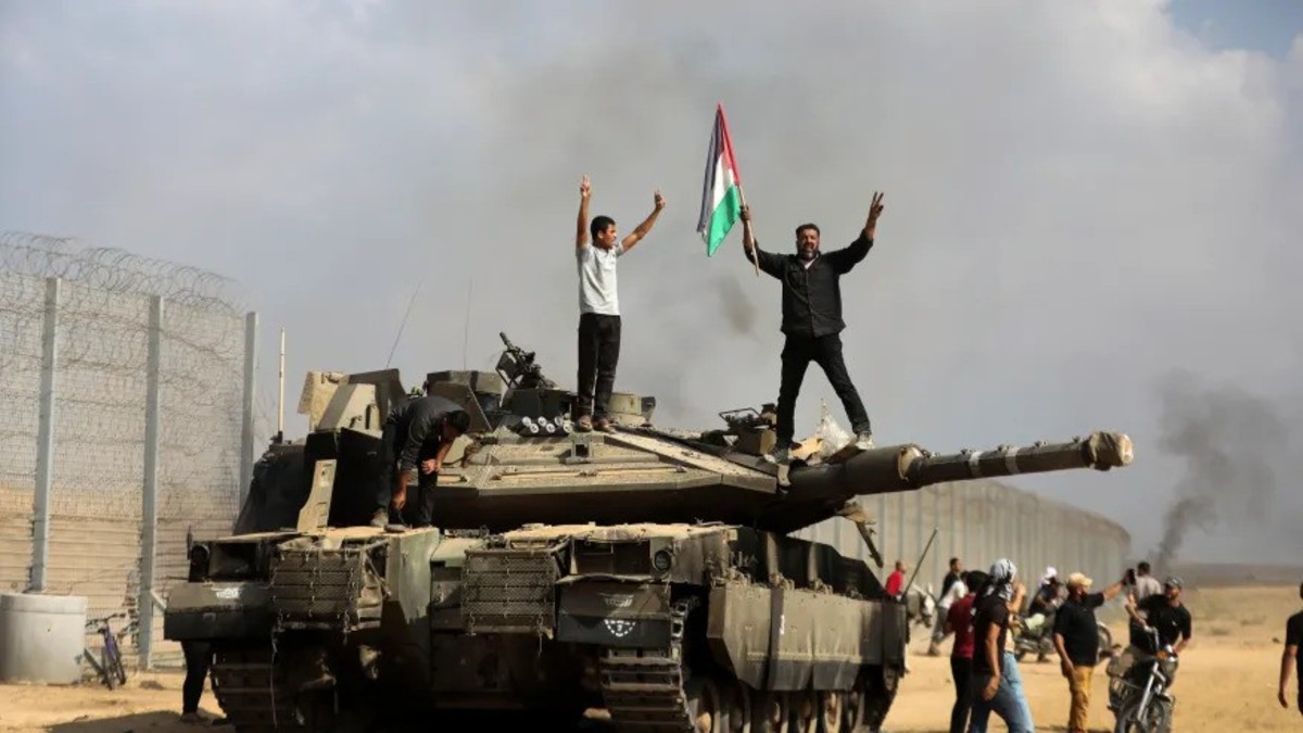 Members of Hamas' armed wing hold a Palestinian flag atop an Israeli tank in the southern Gaza Strip on October 7, 2023. (AP Photo/Yousef Masoud) Members of Hamas' armed wing hold a Palestinian flag atop an Israeli tank in the southern Gaza Strip on October 7, 2023. (AP Photo/Yousef Masoud)