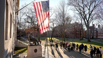 (File) People take photographs near a John Harvard statue, left, on the campus of Harvard University, in Cambridge, Mass. Harvard University. AP
