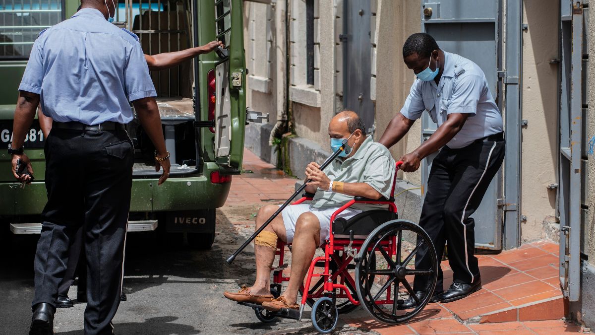Businessman Mehul Choksi is taken to a police van via a wheelchair by a police officer after attending a court hearing, in Roseau, Dominica, June 10, 2021. File Photo/AP Businessman Mehul Choksi is taken to a police van via a wheelchair by a police officer after attending a court hearing, in Roseau, Dominica, June 10, 2021. File Photo/AP