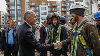 Canada’s Prime Minister Mark Carney shakes hands with a construction worker. Reuters