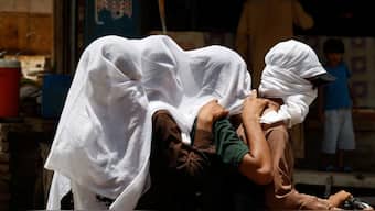 Men ride on a motorbike as they cover their heads with a wet cloth to cool off and to avoid sunlight. Source: Reuters