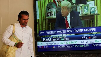 A man walks past a screen displaying US President Donald Trump, at the Bombay Stock Exchange (BSE) ahead of Trump's tariff plans, in Mumbai, India, April 2. The US president is expected to announce reciprocal tariffs at the Rose Garden of the White House. Reuters