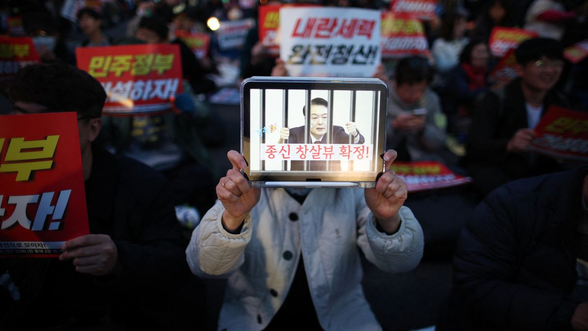 A person holds a tablet displaying image depicting impeached President Yoon Suk Yeol behind jail bars during a rally to celebrate his expulsion, in Seoul, on April 4. Reuters A person holds a tablet displaying image depicting impeached President Yoon Suk Yeol behind jail bars during a rally to celebrate his expulsion, in Seoul, on April 4. Reuters