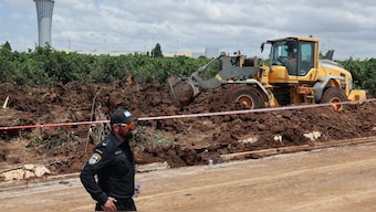 Members of Israeli security services fill up a crater near a road outside Israel's Ben Gurion airport after a missile launched from Yemen struck the area. AFP
