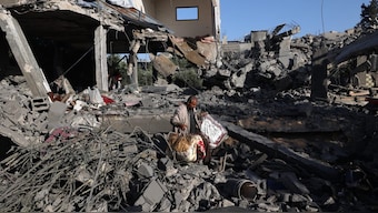 A Palestinian man carries items he salvaged from a house targeted in an Israeli strike at the Nuseirat camp for refugees in the central Gaza Strip. AFP