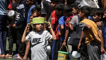 Palestinian children gather to receive a hot meal at a food distribution point in the Nuseirat camp for refugees in the central Gaza Strip. AFP