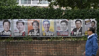 A man walks past banners showing South Korea's presidential candidates displayed along a wall ahead of the upcoming June 3 election in Seoul. AFP
