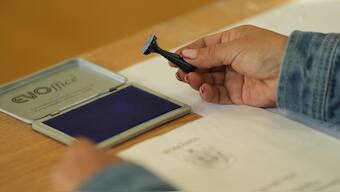 An election official holds a voting stamp during the first round of the presidential election redo in Bucharest, Romania. AP