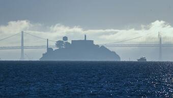 A boat makes its way toward Alcatraz Island with the San Francisco-Oakland Bay Bridge in the background in this view from Sausalito, Calif. File image/ AP