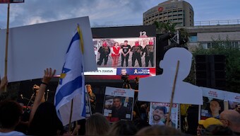 People watch a live broadcast of Israeli-American soldier Edan Alexander as he is released from Hamas captivity in Gaza, at a plaza known as the hostages square in Tel Aviv, on Monday. AP