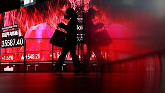 A woman walks in front of big screen displaying Japan's Nikkei share average inside a building in Tokyo, Japan, April 25, 2025. Representational Image/Reuters
