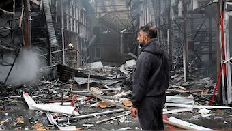 A man stands as a Ukrainian fireman finishes to put out a fire at the "Barabashovo" market following a drone strike in Kharkiv on May 6, 2025 amid the Russian invasion of Ukraine. Image- AFP