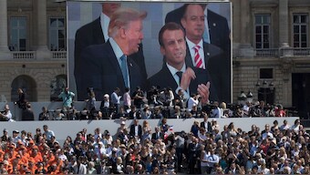 US President Donald Trump, pictured on screen from left, French President Emmanuel Macron and White House Chief of Staff Reince Priebus watch a Bastille Day parade on the Champs Elysees avenue in Paris, July 14, 2017. File Image/AP