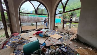 Men are seen through windowpanes of a residential house damaged by a cross-border shelling in Gingal village near the Line of Control (LoC) between India and Pakistan, in Kashmir's Baramulla district, May 9, 2025. Reuters