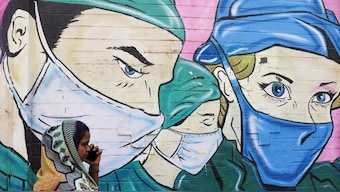 A woman walks past a coronavirus (COVID-19) themed mural on a street in Mumbai, March 28, 2023. File Photo/Reuters