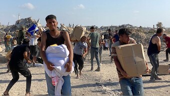 Men look around on alert in the wake of gunfire shots as displaced Palestinians receive food packages from a US-backed foundation pledging to distribute humanitarian aid in western Rafah in the southern Gaza Strip on May 27, 2025. AFP