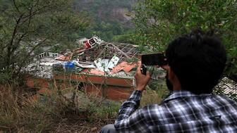 A person snaps a photo of a building fallen after it was hit by an Indian strike in Muzaffarabad. Reuters