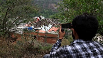 A person snaps a photo of a building fallen after it was hit by an Indian strike in Muzaffarabad. Reuters