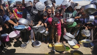 Palestinians struggle to receive cooked food distributed at a community kitchen in the Muwasi area of Khan Younis, in the Gaza Strip. AP
