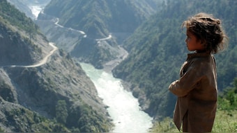 A child stands near Chenab River with the Baglihar hydroelectric project in the background, about 155 km  northwest of Jammu. File photo/Reuters