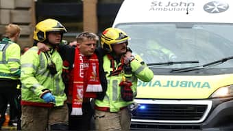 A fan is assisted by fire fighters at an incident involving a car and supporters during the Liverpool FC's victory parade. Reuters