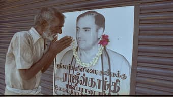An old man pays his tributes to Rajiv gandhi after putting a garland on Gandhi's election campaign poster. File image/Reuters