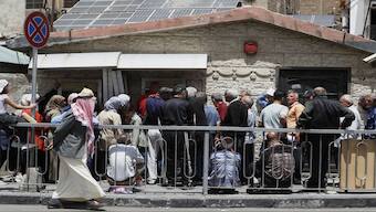 Syrians line up to retrieve money from an ATM in Damascus, Syria. AP