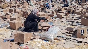 A woman crouches next to boxes of the US-backed Gaza Humanitarian Foundation, as Palestinians gather to collect what remains of relief supplies, in Rafah. Reuters
