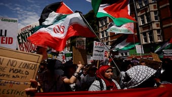  Protesters wave Palestinian and Iranian flags and hold placards reading "Stop arming Israel" as they gather in Russell Square to take part in a march through central London, on June 21, 2025. AFP