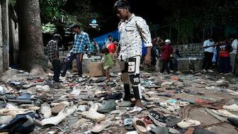 People rummage through footwear strewn outside M. Chinnaswamy Stadium after a stampede caused by frenzied fans celebrating Royal Challengers Bengaluru's victory in the Indian Premier League cricket tournament, in Bengaluru, on Wednesday. AP