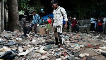 People rummage through footwear strewn outside M. Chinnaswamy Stadium after the stampede. Image: AP