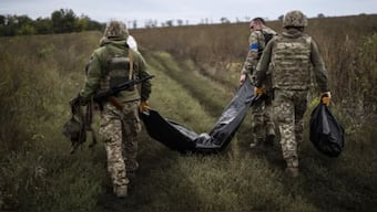 Ukrainian servicemen carry a bag containing the body of a Ukrainian soldier as one of them, right, carries the remains of a body of a Russian soldier in a retaken area near the border with Russia in the Kharkiv region if Ukraine. (Photo: AP)