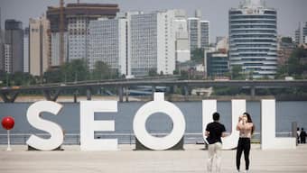 A woman wearing a mask amid the coronavirus disease (COVID-19) pandemic takes photographs of her boyfriend at a Han river park in Seoul, South Korea, May 24, 2021. (Reuters/Kim Hong-Ji)