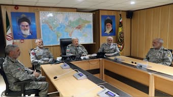 In this photo released on Monday by Iranian army press service, Iran's army commander-in-chief Gen. Amir Hatami, center, accompanied by high ranked army commanders, speaks in a video call with top commanders of the army, in Zolfaghar central headquarters, Iran, as portraits of the late revolutionary founder Ayatollah Khomeini, left, and Supreme Leader Ayatollah Ali Khamenei hang on the wall. AP