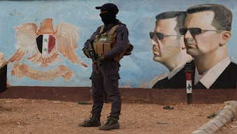 A member of the former rebel group Hayat Tahrir al-Sham stands guard near an image of Syria's Bashar al-Assad at the fourth division headquarters in Damascus, Syria, on January 23, 2025. Reuters File 