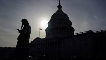 A person uses a mobile phone with the US Capitol building in the background. Reuters