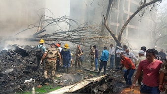 Emergency personnel and other people gather near damaged property, at the site where an Air India plane crashed, in Ahmedabad, June 12, 2025. Reuters