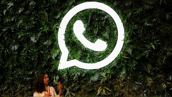 A woman stands next to a logo of messaging application Whatsapp during a Meta conference in Mumbai, India, September 20, 2023. File Image/Reuters