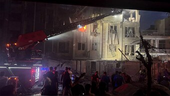 This handout photo released by Iran's Revolutionary Guard Corps (IRGC) official Sepah News Telegram channel on June 13, 2025 shows onlookers and rescue teams in front of a building that caught fire following and Israeli strike on the Iranian capital Tehran early in the morning.